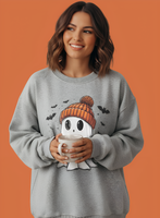 Woman wearing a gray sweatshirt with a ghost design, holding a mug against an orange background