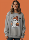 Woman wearing a gray sweatshirt with a Halloween-themed ghost design on an orange background