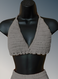 Crocheted beige top on a black mannequin against a gray background