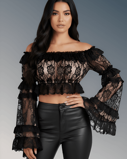 Woman wearing a black lace top and black pants against a gray background