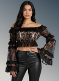 Woman wearing a black lace top and leather pants on a gray background