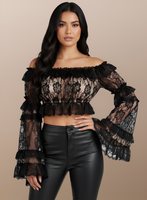 Woman wearing a black lace top and black pants against a beige background