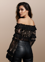 Woman wearing a black off-shoulder top with ruffles and black leather pants on a beige background