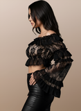 Black lace top worn by a model on a beige background